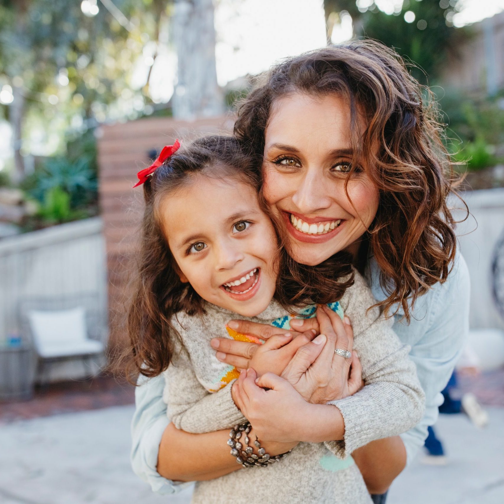 Portrait of happy mother embracing cute daughter while standing in yard